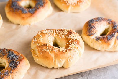 Baked bagels with poppy seeds and sesame seeds on parchment on the table. homemade pastries