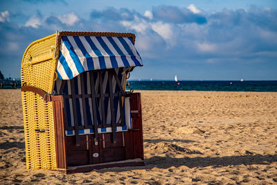 Deck chairs on beach against sky