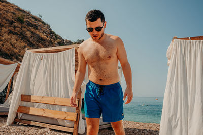 Full length of shirtless man standing at beach