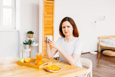 Portrait of woman sitting on table at home