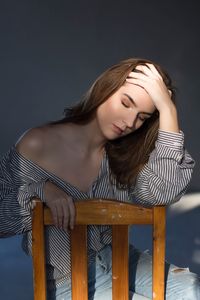 Young woman looking away while standing against wall