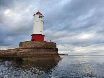 Lighthouse by sea against sky