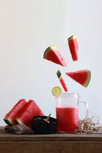 Watermelon slices with juice on table against white background