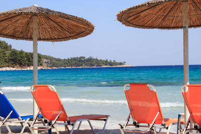 Lounge chairs and parasols on beach against sky