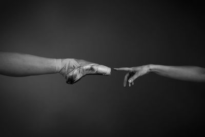 Cropped image of hand reaching leg against gray background