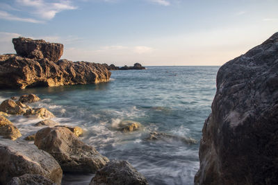 Scenic view of rocks in sea against sky