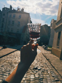 Person holding glass of building in city