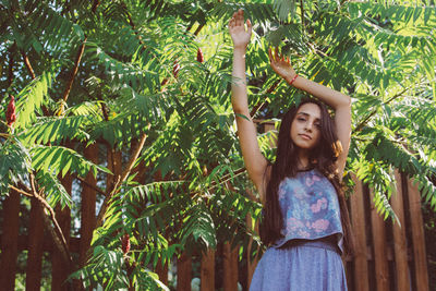 Portrait of young woman standing against tree