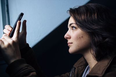 Side view of young woman using mobile phone at home