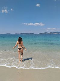 Full length of woman wading in sea against sky