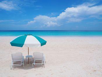 Deck chairs on beach against blue sky