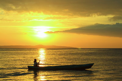 Silhouette man on boat on sea against sky during sunset