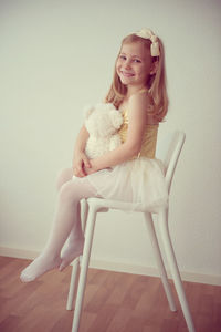 Ballet dancer standing on chair against wall