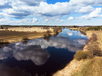 The beautiful clouds reflect on the still water of the river at the rural finland. 