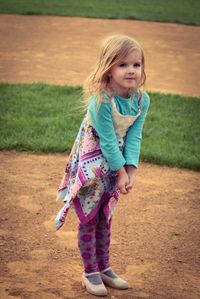 Full length portrait of girl standing on baseball field