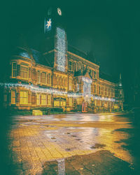 Illuminated building by street against sky at night