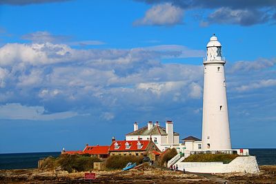 Lighthouse by sea against blue sky