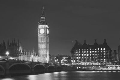 Illuminated big ben by thames river against sky