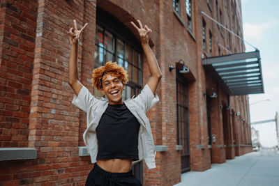 Portrait of young woman standing against building