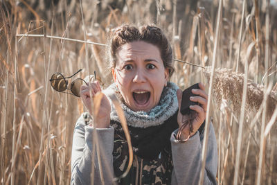 Woman holding mirror compass standing amidst field in forest