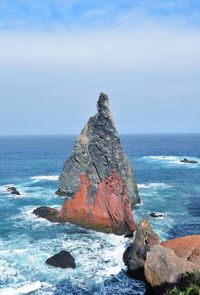 Rock formation on sea shore against sky