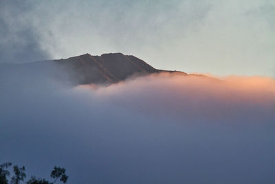 Low angle view of volcanic mountain against sky during sunset