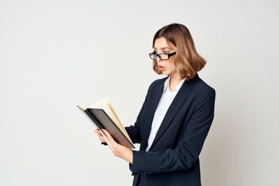 Businesswoman holding book against white background