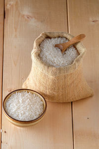 High angle view of sack and bowl with rice on table