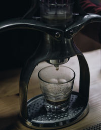 Close-up of coffee pouring from machinery in glass