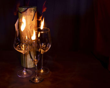 Wineglasses by fire on table in darkroom