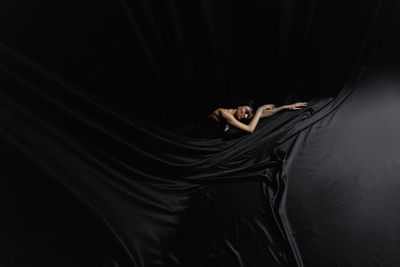 Portrait of woman standing against black background