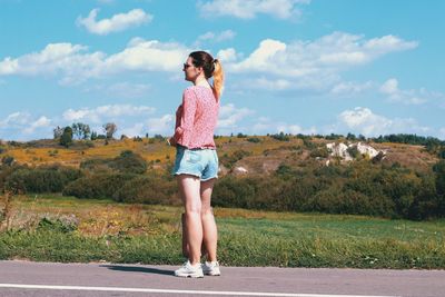 Side view of woman standing on road against sky