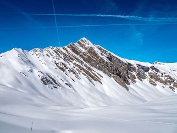 Scenic view of snowcapped mountains against blue sky