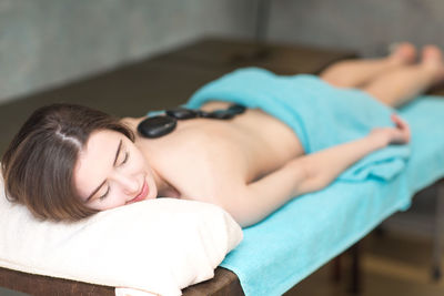 Rear view of woman relaxing on bed at spa