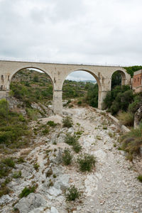 Arch bridge over river against sky