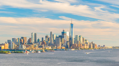 City at waterfront against cloudy sky