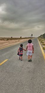 Rear view of women on road against sky