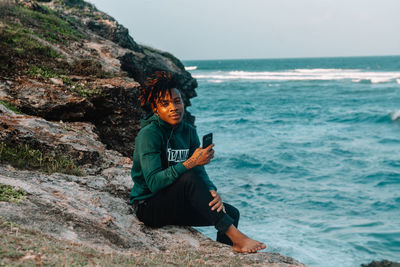 Man sitting on rock at sea shore