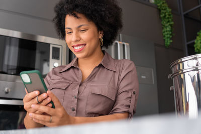 Smiling young woman using mobile phone outdoors