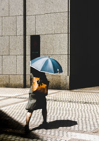 Low section of woman with umbrella on tiled floor