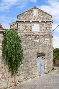 A quiet, medieval-style stone village street featuring a cobblestone path, ivy-draped walls.