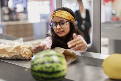 Girl standing at till in supermarket