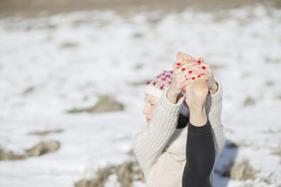 Midsection of woman standing at beach during winter