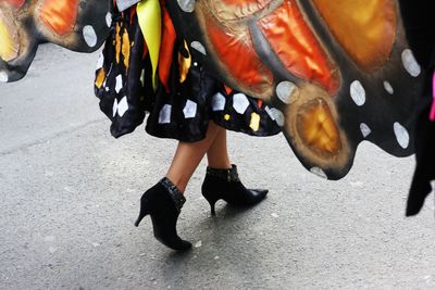 Low section of woman wearing high heels walking on road