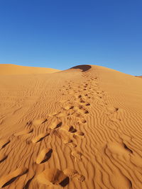 Sand dunes in desert against clear blue sky