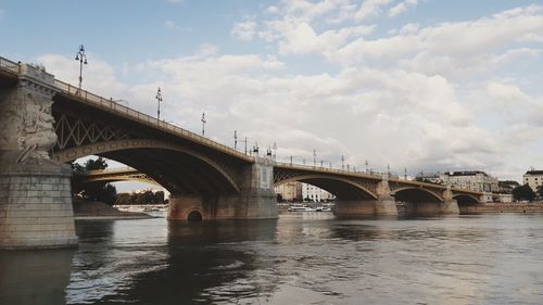 Bridge over river against sky in city