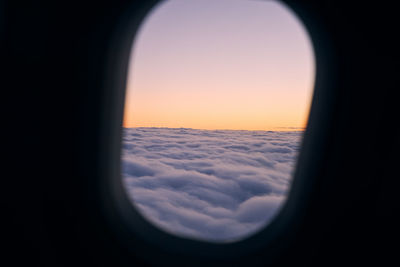 View from airplane window during flight above clouds at beautiful sunset.