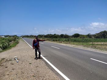 Rear view of man walking on road against sky