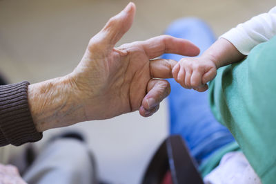 Baby holding finger of her great grandmother's hand