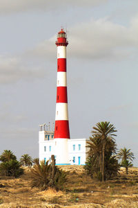 Lighthouse by building against sky